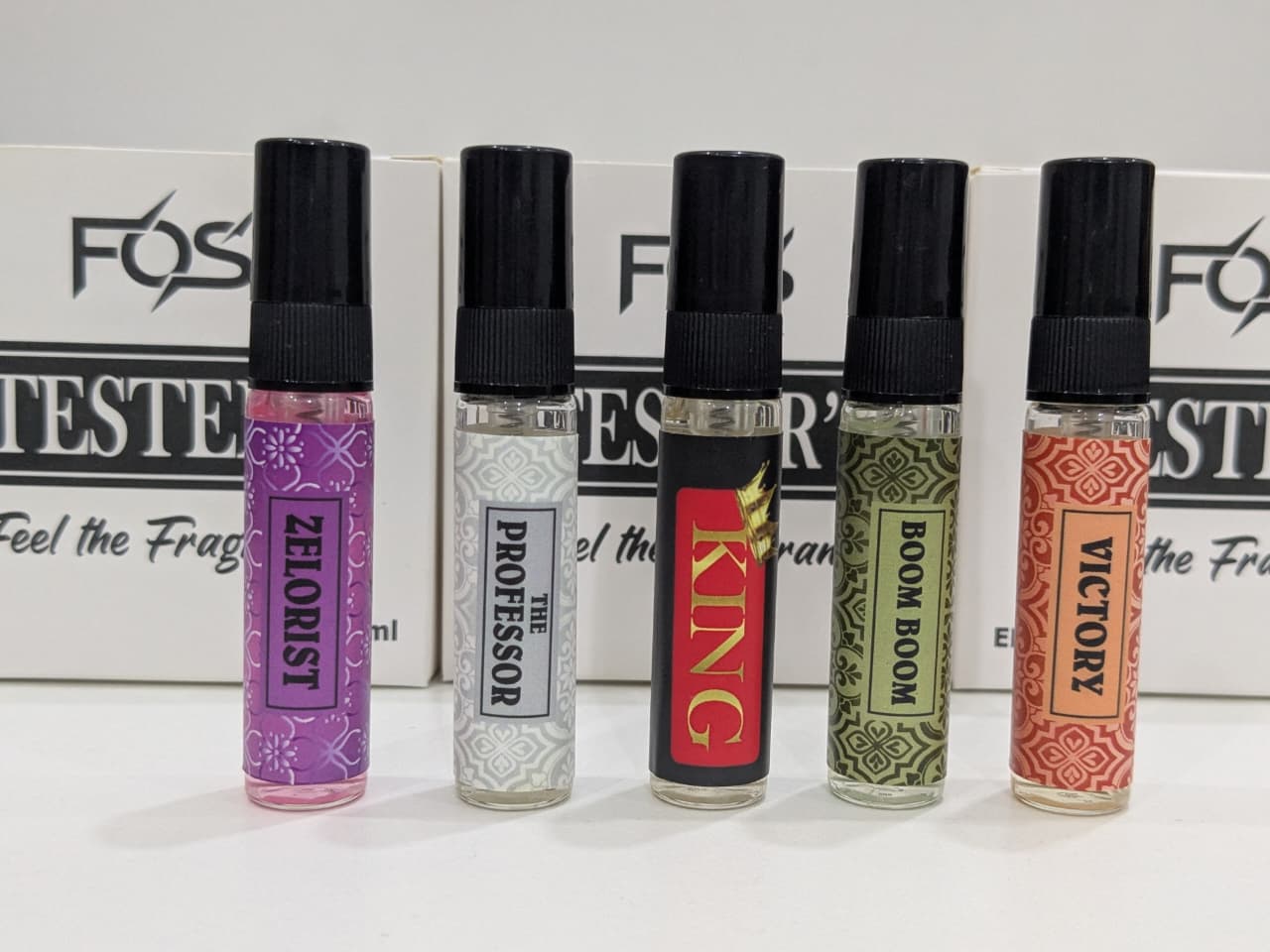Five small bottles with colorful labels and black caps on a white background.