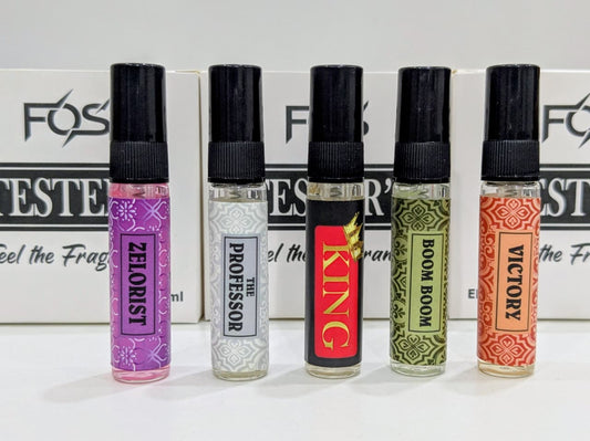 Five small perfume bottles with different labels in front of a branded backdrop.